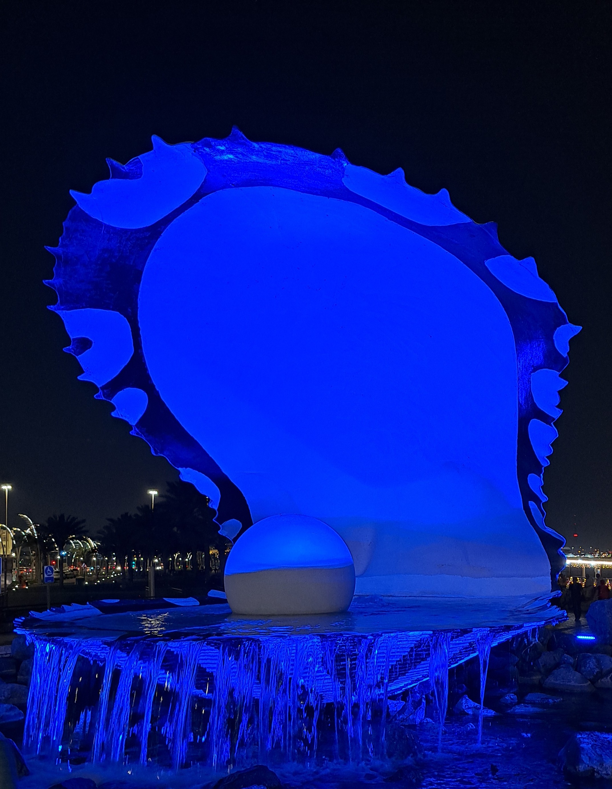 Blue lit up Pearl Monument at night in Doha
